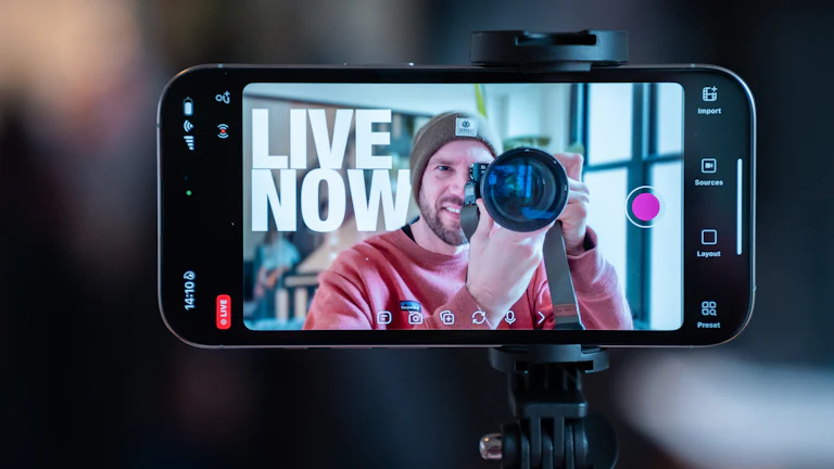 A creator films himself with a camera through a smartphone on a tripod